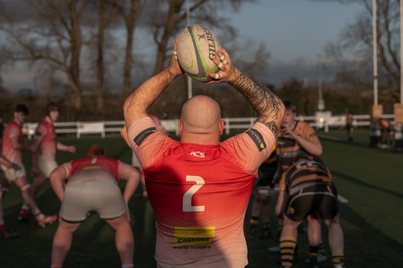 A rugby player prepares to throw a ball during a game on a field with other players in the background.